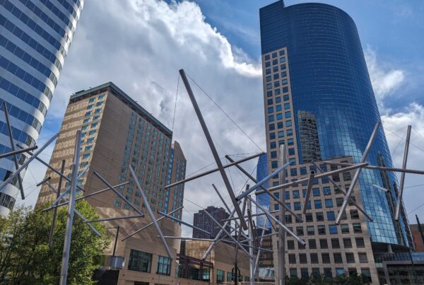 Photo taken in downtown Denver of a sculpture entitled "Soft Landing" with high rise buildings in the background.