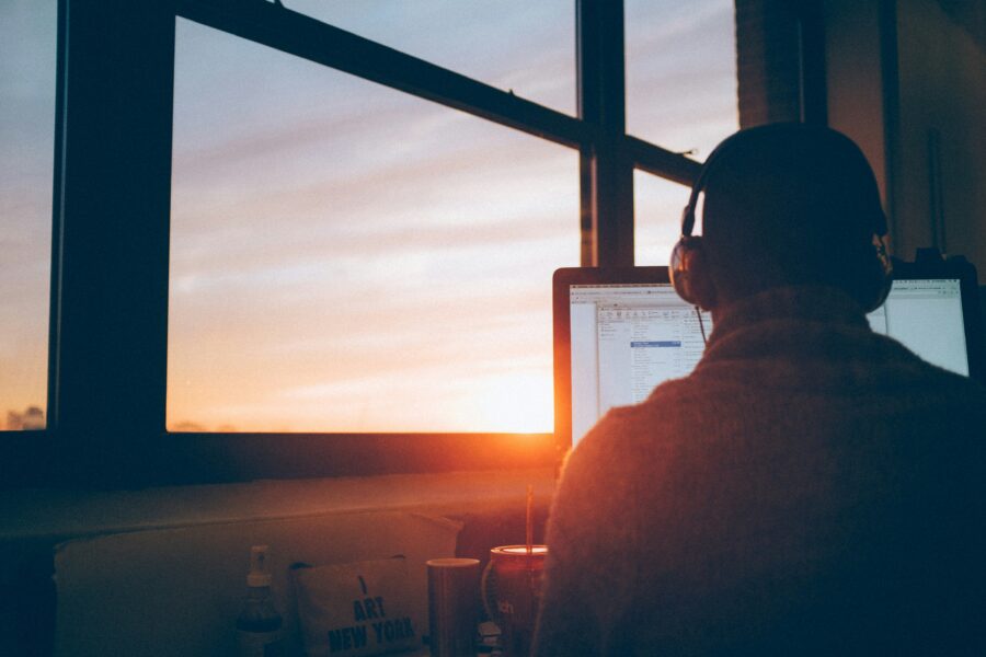 Person working on a computer near a window with a sunrise in the background